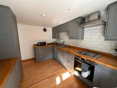 a kitchen with gray cabinets and a wooden floor at Curlew Cottage - Peaceful Setting Stunning Views in Bruichladdich