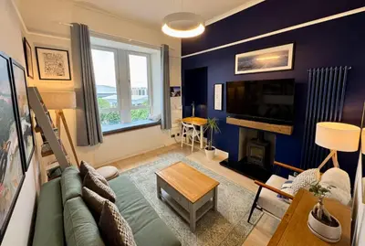 a living room with a green couch and a fireplace at Warm upgraded top-floor flat in Finnieston in Glasgow