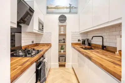 a kitchen with white walls and wooden counter tops at Warm upgraded top-floor flat in Finnieston in Glasgow