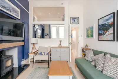 a living room with a green couch and a fireplace at Warm upgraded top-floor flat in Finnieston in Glasgow