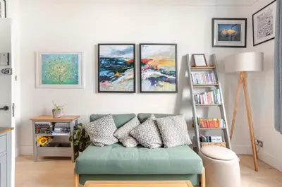 a living room with a green couch and four paintings at Warm upgraded top-floor flat in Finnieston in Glasgow