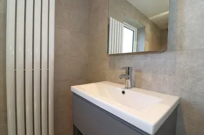 a bathroom with a white sink and a radiator at Signature - Duncan House in Wishaw