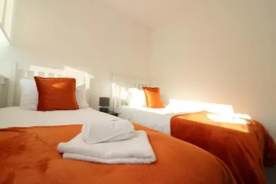 two beds in a room with orange and white at Signature - Duncan House in Wishaw