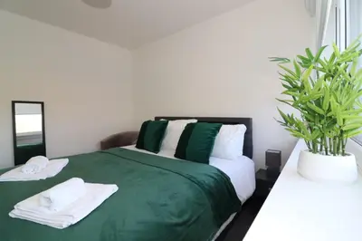 a bedroom with a green bed with towels and a plant at Signature - Duncan House in Wishaw