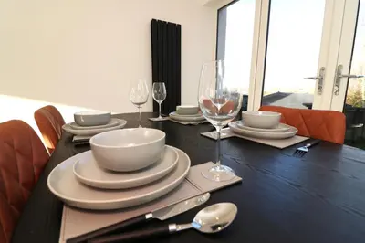 a black table with plates and wine glasses on it at Signature - Duncan House in Wishaw