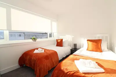 two beds in a room with a window at Signature - Duncan House in Wishaw