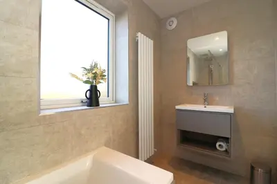 a bathroom with a tub and a sink and a window at Signature - Duncan House in Wishaw