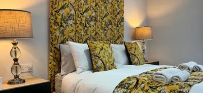 a bedroom with a bed with two lamps at Belstane Manor in Carluke