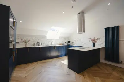 a kitchen with blue cabinets and a white wall at Old Church Apartment 5 in Oban