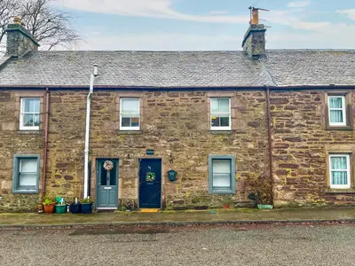 an old brick house with a blue door at The Montrose in Muthill