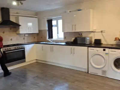 a kitchen with white cabinets and a washer and dryer at Akwaaba services in Moffat