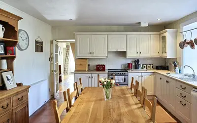 a kitchen with a table with a vase of flowers on it at Glenalbyn Cottage in Saint Fillans