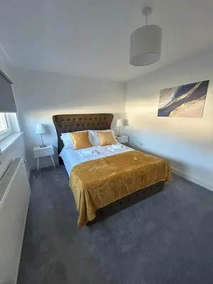 a bedroom with a bed with a gold bedspread at Plains Town House, Airdrie in Caldercruix
