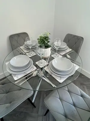 a glass table with plates and wine glasses on it at Plains Town House, Airdrie in Caldercruix