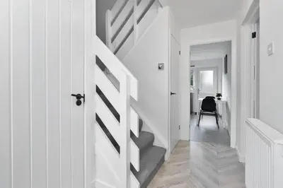 a hallway with white walls and stairs with a door at Stylish 4Bed Home Free Parking 20 Min to Edinburgh in Livingston