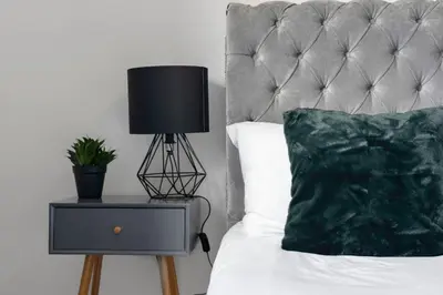 a bed with a black lamp on a night stand at Stylish 4Bed Home Free Parking 20 Min to Edinburgh in Livingston