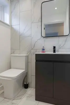 a bathroom with a toilet and a sink and a mirror at Stylish 4Bed Home Free Parking 20 Min to Edinburgh in Livingston
