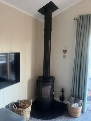 a black stove in a corner of a room at The Eden, Cosy 1 bed lodge with riverside views in Crieff