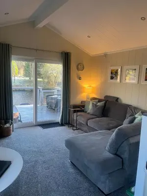 a living room with a couch and a sliding glass door at The Eden, Cosy 1 bed lodge with riverside views in Crieff