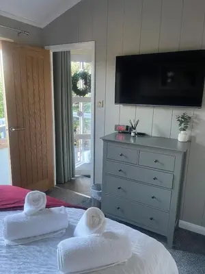 a bedroom with two towels on a bed with a dresser at The Eden, Cosy 1 bed lodge with riverside views in Crieff