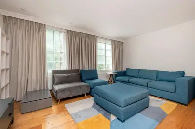 a living room with a blue couch and a chair at Knightsbridge Duplex Two Bedroom Apartment in Moffat