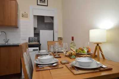 a kitchen with a table with plates and wine glasses at Secret Coast Getaway in Tighnabruaich