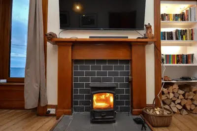 a fireplace in a living room with a tv above it at Secret Coast Getaway in Tighnabruaich