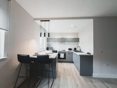 a kitchen with white counters and a table and chairs at Finnieston Apartment in Glasgow