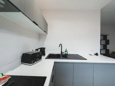 a white kitchen with a sink and a counter at Finnieston Apartment in Glasgow