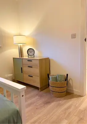 a bedroom with a bed and a dresser and a clock at 7 min from Edinburgh Airport 2 Bedroom Apartment in Edinburgh