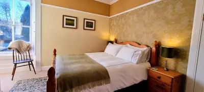 a bedroom with a bed and a chair and a window at Craigbuie Guesthouse in Killin