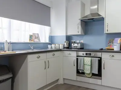 a kitchen with white cabinets and a blue wall at Collegelands in Glasgow in Glasgow