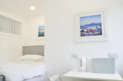 a white bedroom with a bed and a picture on the wall at Viewpoint Pods in Dunollie
