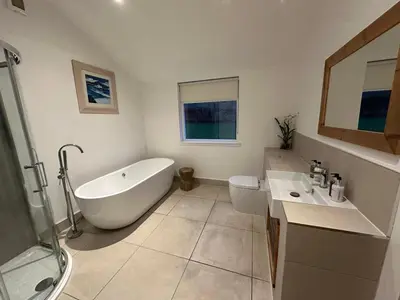 a bathroom with a tub and a toilet and a sink at Ardeonaig Lodge with Hot Tub & Water Fronted Games room in Ardeonaig
