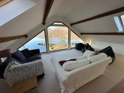 a living room with two couches and a large window at Ardeonaig Lodge with Hot Tub & Water Fronted Games room in Ardeonaig