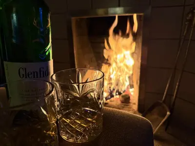 a bottle of wine and a glass next to a fireplace at Ardeonaig Lodge with Hot Tub & Water Fronted Games room in Ardeonaig