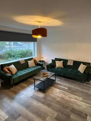 a living room with two green couches and a table at 3BR Home Sleeps 10 with Private Drive Near Park in Newton Mearns
