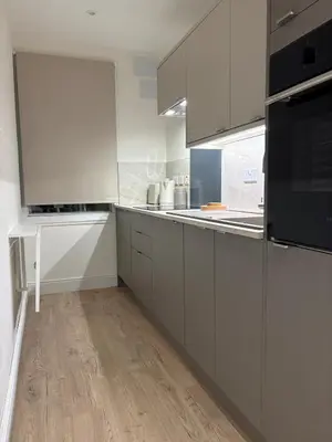 a kitchen with white cabinets and black appliances at Castle flat in Edinburgh in Edinburgh