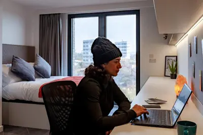 a woman sitting at a desk with a laptop at For Students Only Stylish Studios in Glasgow in Glasgow
