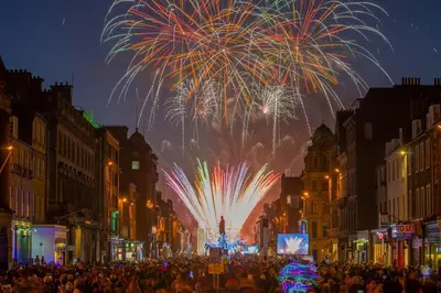a crowd of people on a city street with fireworks at Heart Of Edinburgh City Flat in Edinburgh