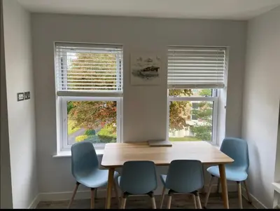 a dining room table with four chairs and two windows at The Palms in Moffat