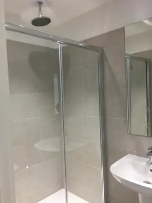 a shower with a glass door next to a sink at The Palms in Moffat