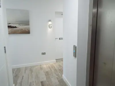 a hallway with a white wall with a painting on it at The Palms in Moffat