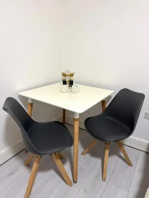 a table with two chairs and a white table with a table at Cozy Golders Green Studio Flat in Moffat