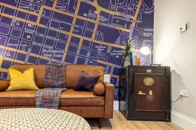 a living room with a couch and a wall with a map at The Steamie on Bath St in Glasgow
