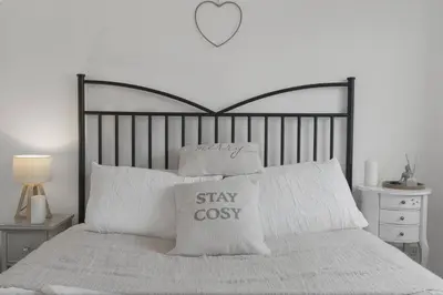 a bed with white pillows and a heart on the wall at Cozy Edinburgh 2BR with CAR parking in Edinburgh