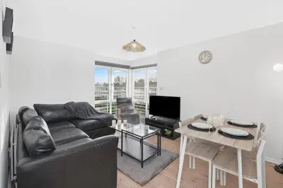 a living room with a black couch and a table at Cozy Edinburgh 2BR with CAR parking in Edinburgh
