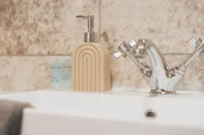 a soap dispenser sitting next to a sink at Top Floor 1BR Wishaw Flat with Parking in Wishaw