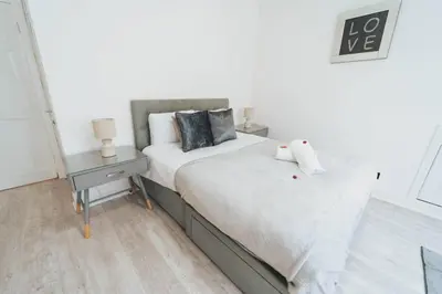 a bedroom with a bed and a night stand with two lamps at Top Floor 1BR Wishaw Flat with Parking in Wishaw