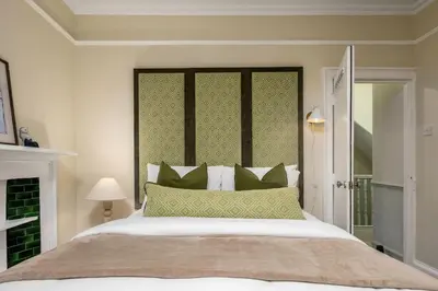 a bedroom with a large bed with green pillows at 3-Bed Georgian Townhouse Next to Wellbeing Clinic in Stirling
